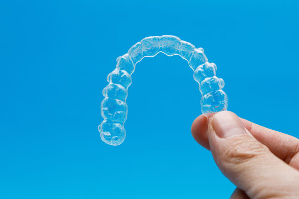Persona sosteniendo un retenedor Invisalign.